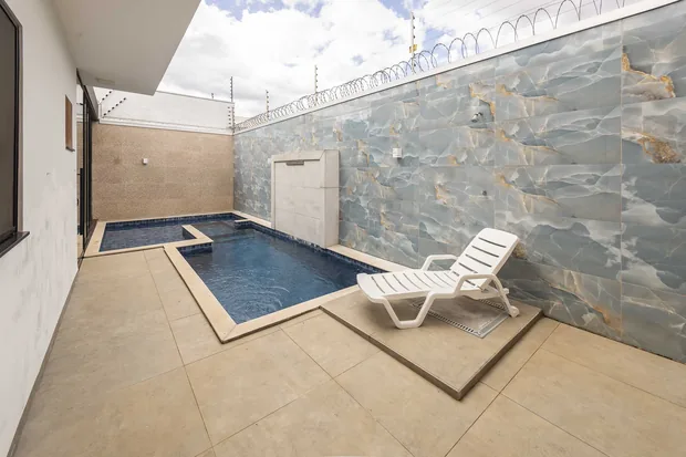 Espreguiçadeira na beira da piscina, junto à parede de pedra