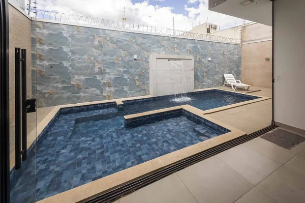 Piscina com a parede de pedra vista de dentro do salão