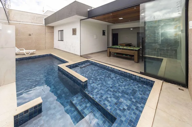 Piscina com a prainha e o salão envidraçado ao fundo