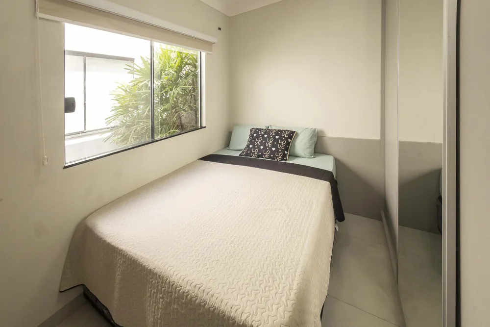 Quarto com cama de casal, armário com espelho e janela para o jardim