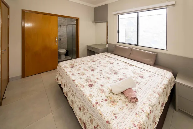 Suíte com cama de casal e a porta do banheiro