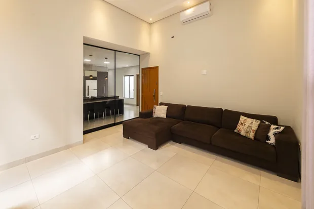 Sala ampla com sofá de canto e a porta de vidro para a cozinha