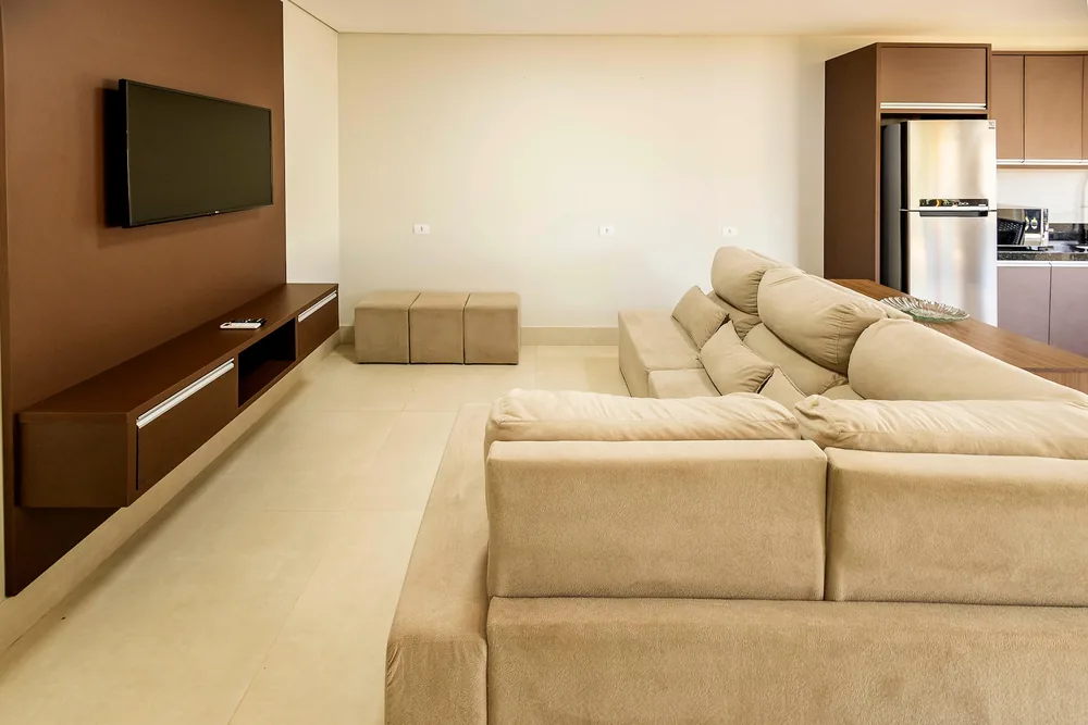 Sala de estar com sofá claro e TV